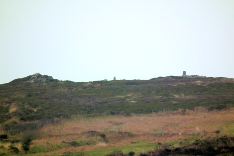 A cairn (on the right, with a modern trig point on it) on Watch Croft, as seen from downhill at Men Scryfa. Middle, a menhir, placed to be seen from Men Scryfa. Left, a natural crag, but energetic.